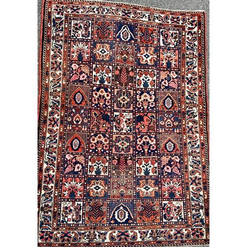 1284 - A Persian Baktiari hand-knotted carpet with central field of forty five floral and geometric panels,... 