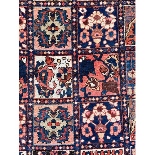 1284 - A Persian Baktiari hand-knotted carpet with central field of forty five floral and geometric panels,... 