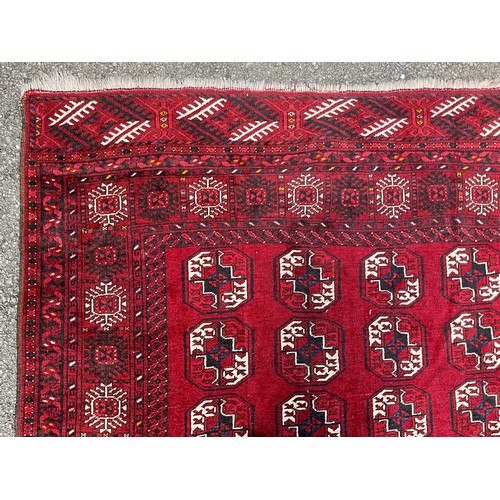 1286 - A Tekke Torkman hand-knotted rug, with four bands of geometric guls, in white, black and blue on red... 