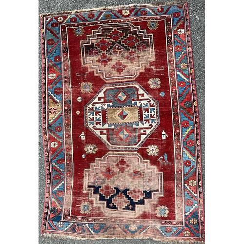 1288 - A 19th century Caucasian Kazak rug, with three principle medallions or red field within twin floral ... 