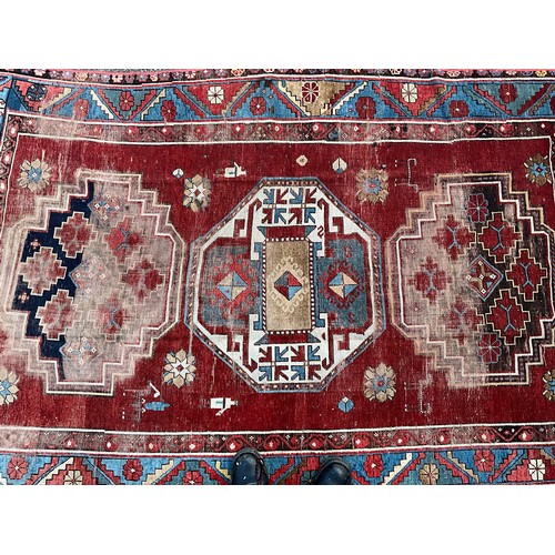 1288 - A 19th century Caucasian Kazak rug, with three principle medallions or red field within twin floral ... 