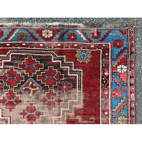 1288 - A 19th century Caucasian Kazak rug, with three principle medallions or red field within twin floral ... 