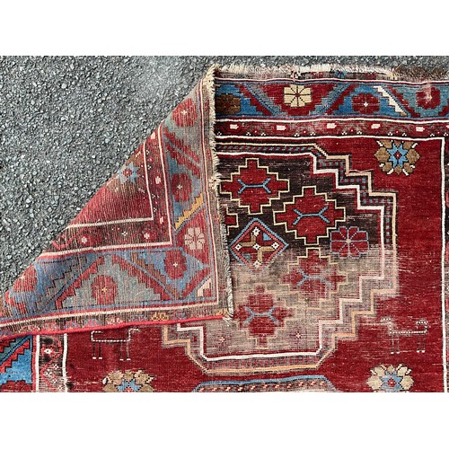 1288 - A 19th century Caucasian Kazak rug, with three principle medallions or red field within twin floral ... 