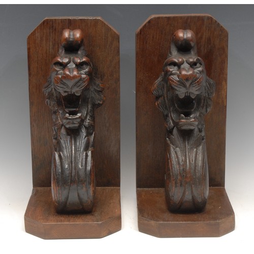 3167 - A pair of substantial oak country house bookends, the scrolling brackets boldly carved with lion mas... 