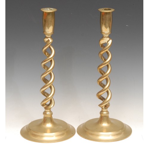 3153 - A pair of early 20th century brass open-twist candlesticks, spreading circular bases, 30.5cm high