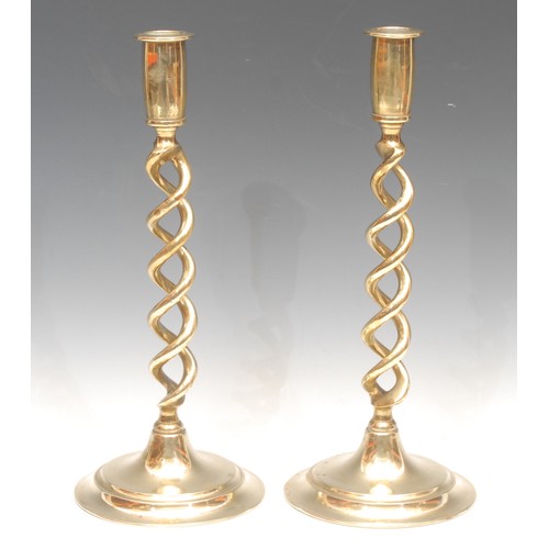 3154 - A pair of early 20th century brass open-twist candlesticks, spreading circular bases, 30.5cm high