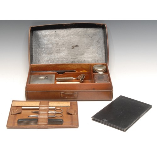 3293 - An early 20th century leather gentleman's dressing case, hinged cover enclosing an arrangement of ac... 