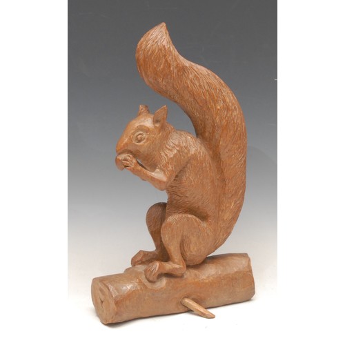 3301 - An early 20th century oak carving, of a squirrel eating an acorn, 33cm high