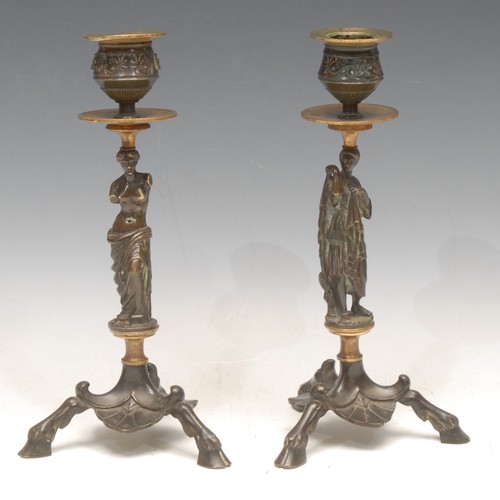 3139 - A pair of 19th century Grand Tour parcel-gilt and brown patinated bronze sculptural tripod candlesti... 