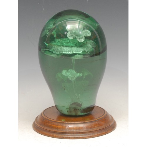 3214 - A Victorian green glass dump weight, decorated with flowers issuing from a vase, turned wooden base,... 