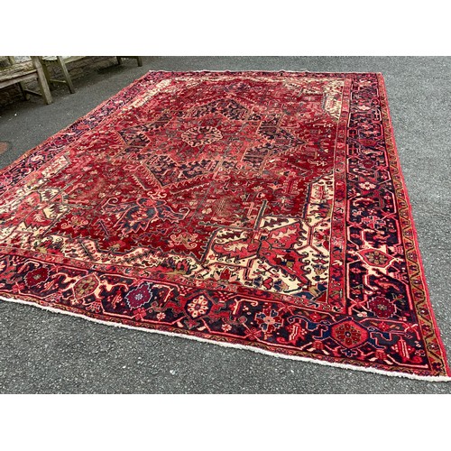 1086 - A Persian Heriz carpet, central geometric floral medallion within red ground, surrounded by triple l... 