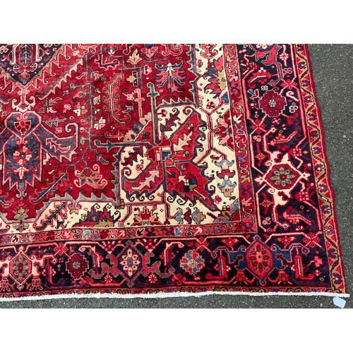 1086 - A Persian Heriz carpet, central geometric floral medallion within red ground, surrounded by triple l... 