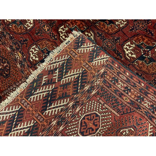 130 - A Turkman Bokhara rug, hand-knotted, typical repeating geometric design, in red with black, orange, ... 