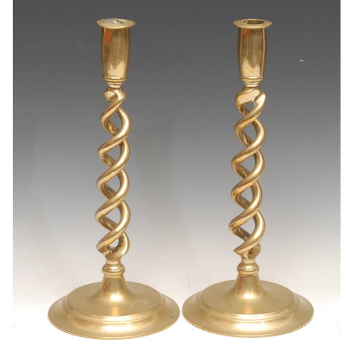 26 - A pair of early 20th century brass open-twist candlesticks, spreading circular bases, 30.5cm high