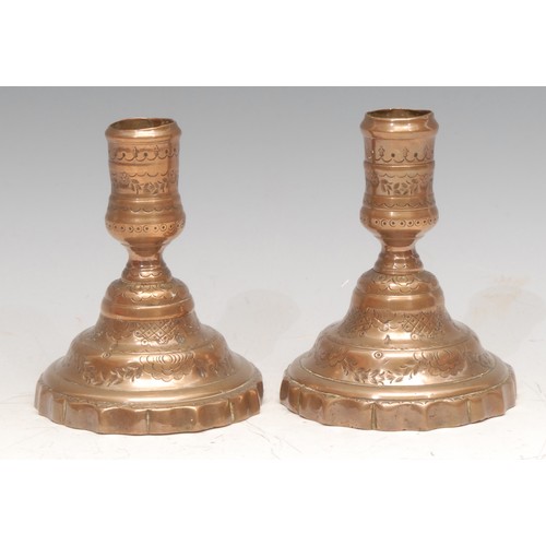 32 - A pair of 19th century bell metal low candlesticks, chased with diapers, swags and stiff leaves, sha... 