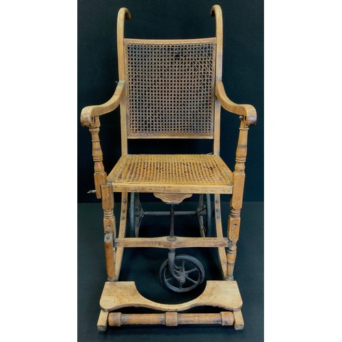 229 - A late 19th century oak framed wheel chair, cane work seat and back, with makers plaque to rear 'Joh... 