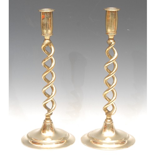 54 - A pair of early 20th century brass open-twist candlesticks, spreading circular bases, 30.5cm high