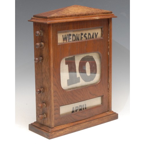 217 - A large early 20th century oak perpetual desk calendar, sarcophagus cresting above glazed apertures ... 