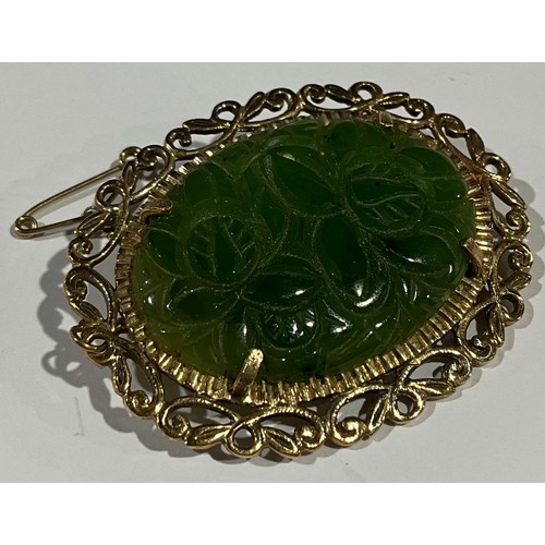 589 - A 9ct gold mounted carved jadeite oval brooch, the green panel with leafy flower heads, openwork scr... 