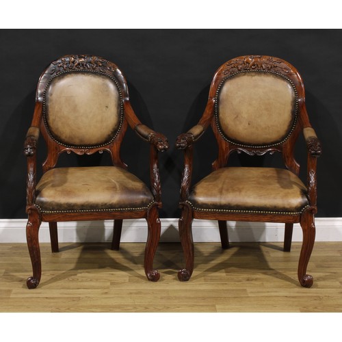 1541 - A pair of 19th century Anglo-Indian colonial padouk elbow chairs, each cresting rail carved with an ... 