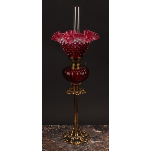 1302 - An Art Nouveau period brass oil lamp, the cranberry and vaseline glass frill top shade moulded with ... 