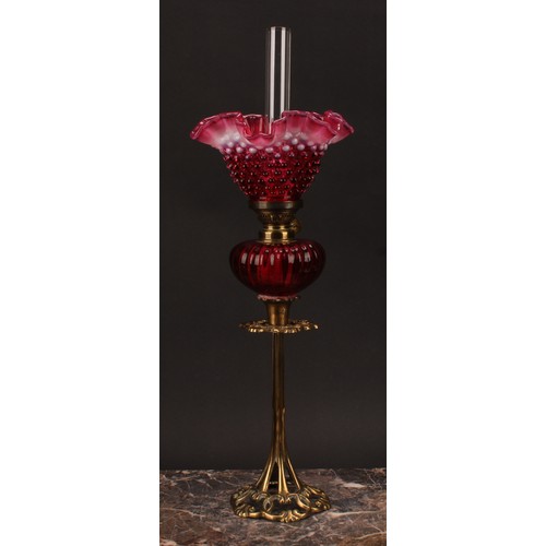 1302 - An Art Nouveau period brass oil lamp, the cranberry and vaseline glass frill top shade moulded with ... 