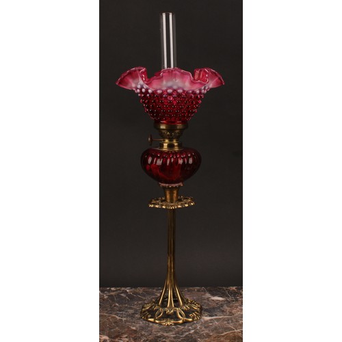 1302 - An Art Nouveau period brass oil lamp, the cranberry and vaseline glass frill top shade moulded with ... 