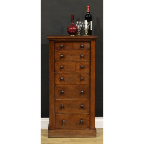 1198 - A late Victorian oak veneered Wellington chest, oversailing rectangular top above seven drawers, pli... 