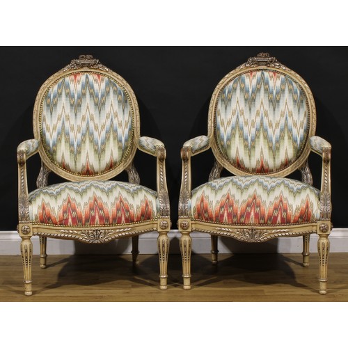 1278 - A pair of Louis XVI Revival painted fauteuils or open armchairs, each cresting carved and applied wi... 