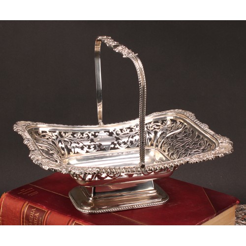 666 - A George V silver shaped rectangular swing-handled pedestal basket, pierced with foliate scrolls, ga... 