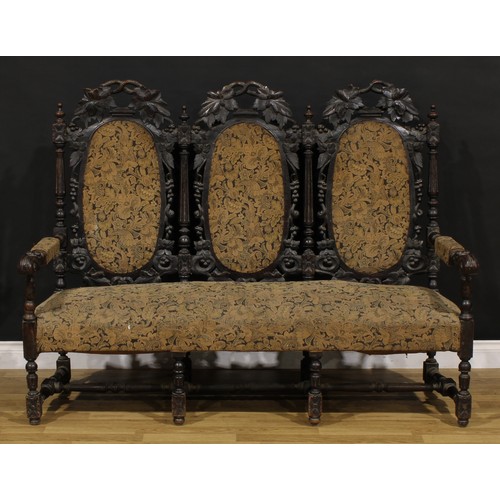 1197 - A late Victorian oak triple-chair-back sofa, stuffed-over upholstery, the back carved throughout wit... 