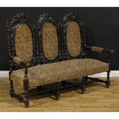 1197 - A late Victorian oak triple-chair-back sofa, stuffed-over upholstery, the back carved throughout wit... 