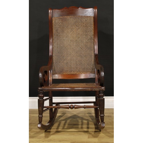 1355 - A Victorian mahogany rocking chair, cane back and seat, scroll arms, 106.5cm high, 56cm wide, the se... 