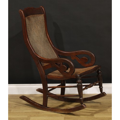 1355 - A Victorian mahogany rocking chair, cane back and seat, scroll arms, 106.5cm high, 56cm wide, the se... 