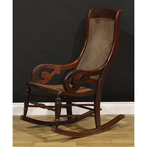 1355 - A Victorian mahogany rocking chair, cane back and seat, scroll arms, 106.5cm high, 56cm wide, the se... 