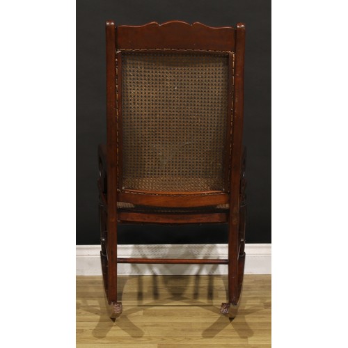 1355 - A Victorian mahogany rocking chair, cane back and seat, scroll arms, 106.5cm high, 56cm wide, the se... 