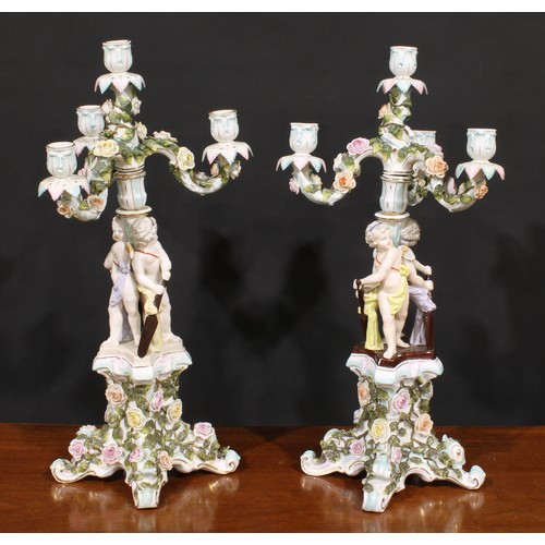 151 - A pair of Sitzendorf porcelain four-light figural candelabra, each modelled as putti holding oars an... 