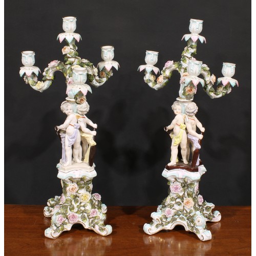 151 - A pair of Sitzendorf porcelain four-light figural candelabra, each modelled as putti holding oars an... 