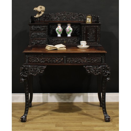 1223 - A Chinese export hardwood desk, shaped superstructure with an arrangement of drawers and a panel doo... 