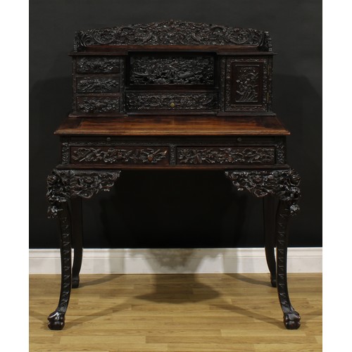 1223 - A Chinese export hardwood desk, shaped superstructure with an arrangement of drawers and a panel doo... 