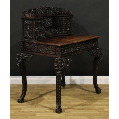 1223 - A Chinese export hardwood desk, shaped superstructure with an arrangement of drawers and a panel doo... 