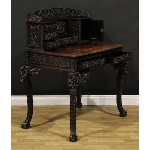 1223 - A Chinese export hardwood desk, shaped superstructure with an arrangement of drawers and a panel doo... 