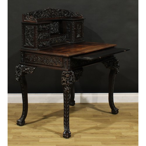 1223 - A Chinese export hardwood desk, shaped superstructure with an arrangement of drawers and a panel doo... 