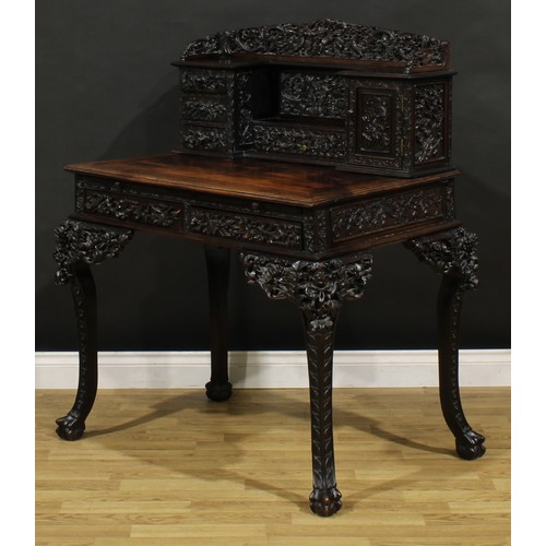 1223 - A Chinese export hardwood desk, shaped superstructure with an arrangement of drawers and a panel doo... 