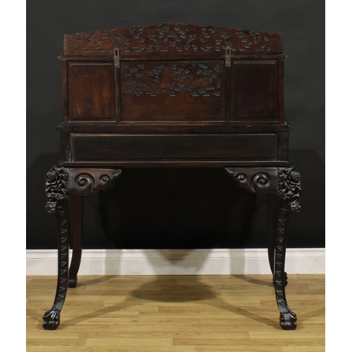 1223 - A Chinese export hardwood desk, shaped superstructure with an arrangement of drawers and a panel doo... 