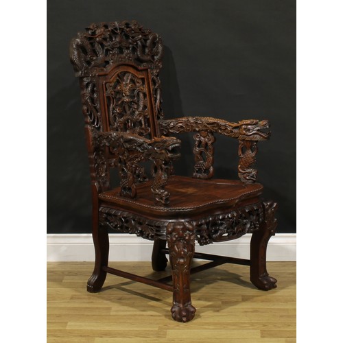 1228 - A Chinese hardwood armchair, carved throughout with dragons and stylised clouds, serpentine seat wit... 