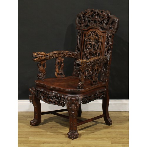 1228 - A Chinese hardwood armchair, carved throughout with dragons and stylised clouds, serpentine seat wit... 