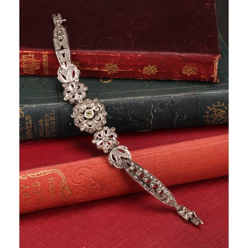 933 - A Belle Époque diamond and white metal bracelet, centered with three graduated flowerheads flanked b... 