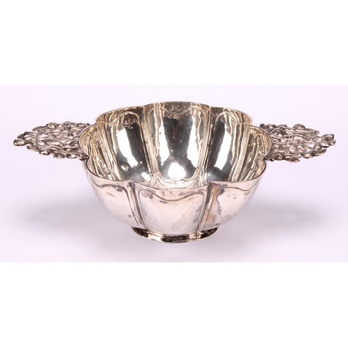 609 - A Dutch silver brandy bowl, of typical lobed design, lug handles pierced and chased with putto and f... 