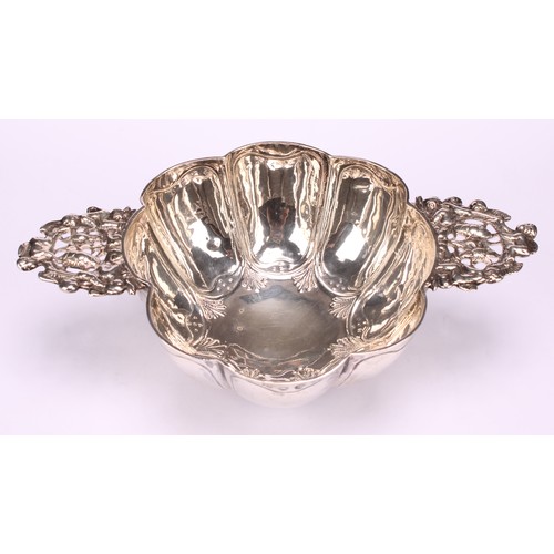 609 - A Dutch silver brandy bowl, of typical lobed design, lug handles pierced and chased with putto and f... 